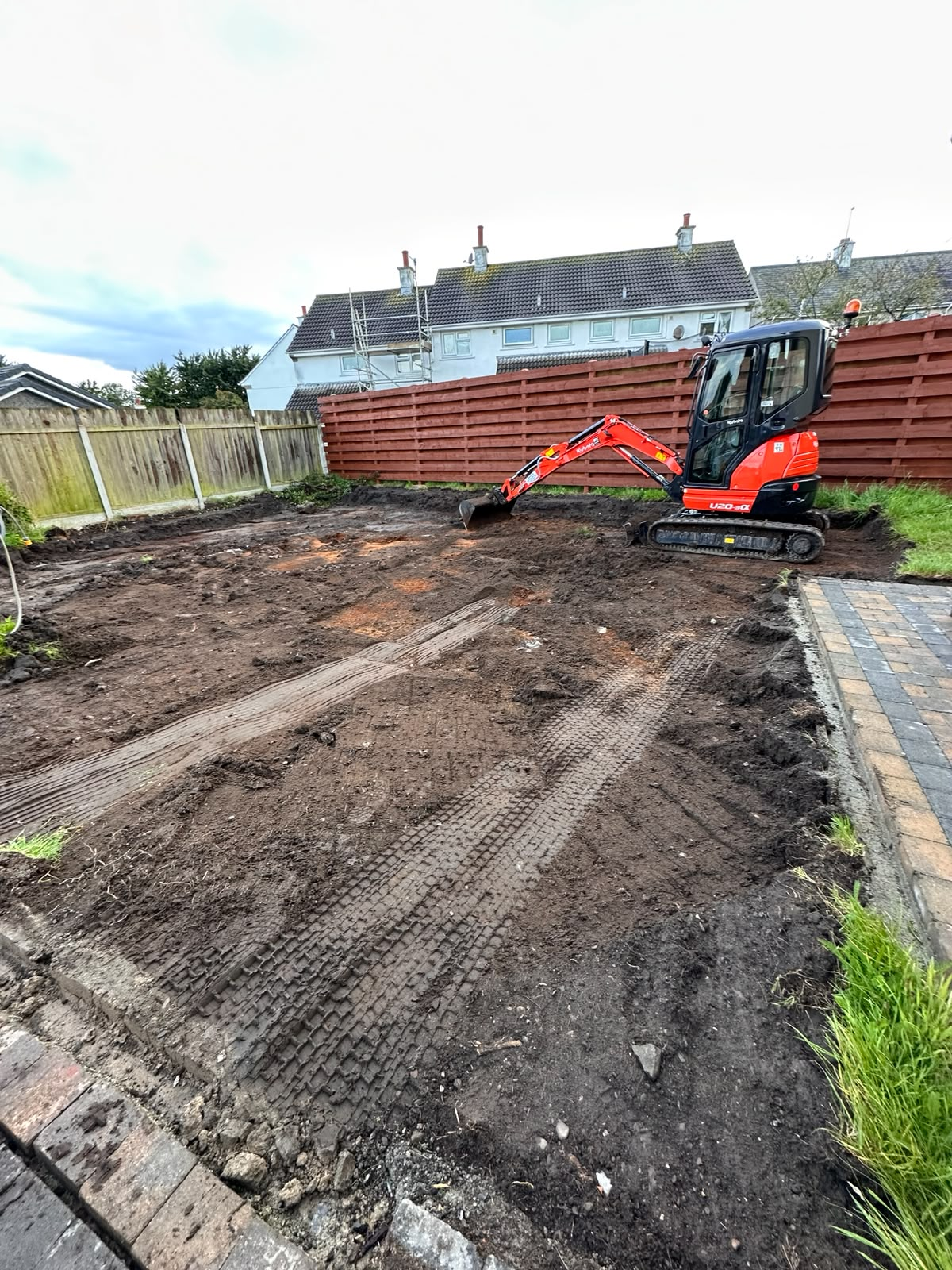 Site clearance and excavation underway with a mini excavator preparing the plot for a detached triple garage, Isle of Man